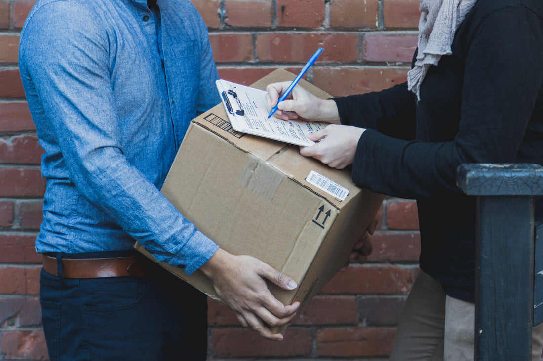 A man holding a shipping box and another signing for it